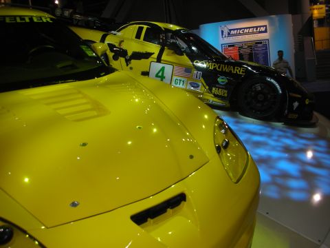 1998 Ford Crown Victoria - Close view over a yellow Corvette's hood toward a black Compuware number-4 GT1 race Corvette indoors.