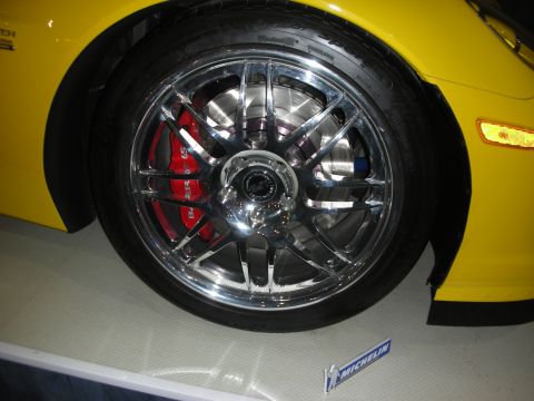 1998 Ford Crown Victoria - Chrome multi-spoke wheel with a red brake caliper mounted on a yellow Corvette over a Michelin display.