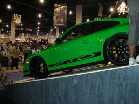 1998 Ford Crown Victoria - Bright green Porsche 911 GT3 RS with black wheels and yellow calipers raised on a platform at an indoor show.