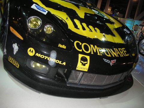 1998 Ford Crown Victoria - Close-up of the black and yellow nose of a Compuware-sponsored C6.R Corvette race car covered in sponsor decals.