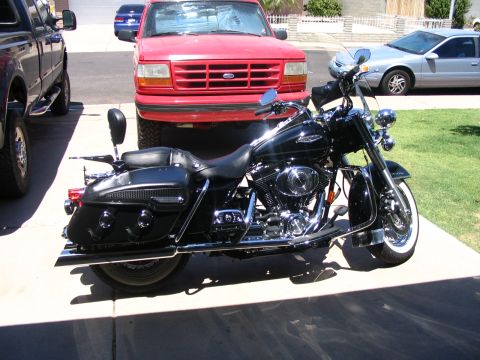2006 Harley-Davidson FLH - A black 2006 Harley-Davidson FLH motorcycle is parked in a driveway, with other vehicles visible in the background.