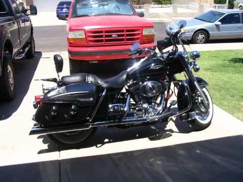 2006 Harley-Davidson FLH - A black 2006 Harley-Davidson FLH motorcycle is parked in front of a red Ford truck.
