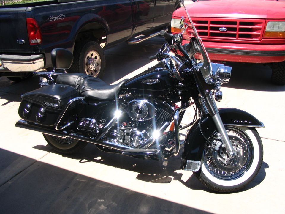 Black Harley-Davidson touring motorcycle with saddlebags and whitewall tires parked on a driveway