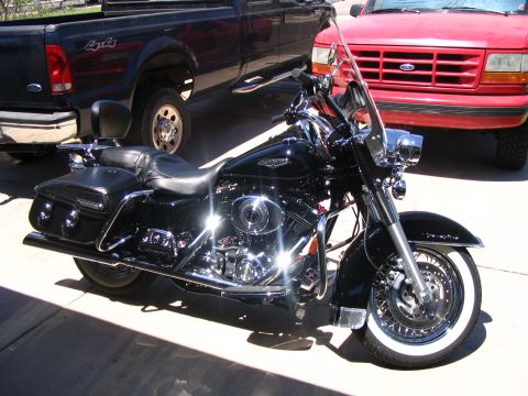 2006 Harley-Davidson FLH - A shiny black 2006 Harley-Davidson FLH motorcycle is parked in a driveway with two trucks behind it.