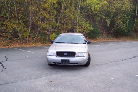 2001 Ford Crown Victoria - A silver 2004 Ford Crown Victoria is parked in an asphalt lot with trees in the background.