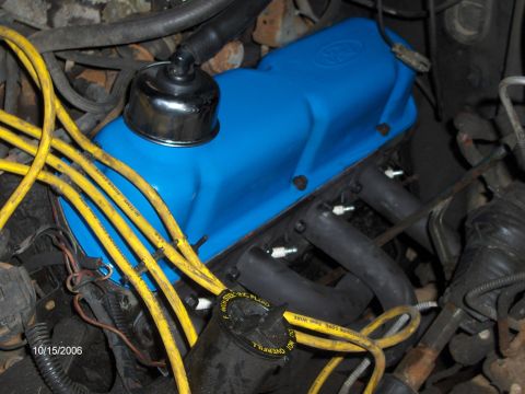 1986 Ford Bronco - Close-up of a blue Ford valve cover and yellow spark plug wires in an engine bay.