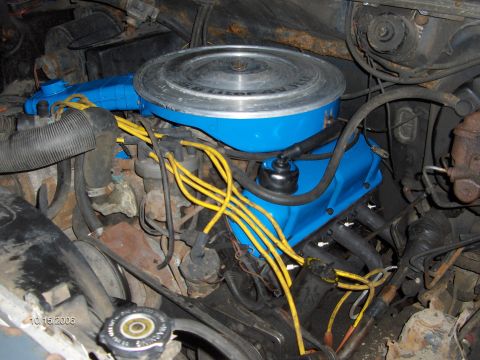 1986 Ford Bronco - Close-up of an engine bay blue valve covers and yellow spark plug wires.