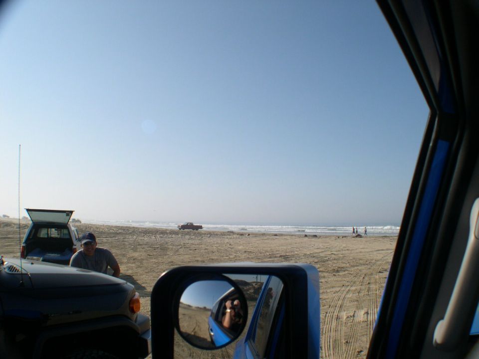 View from inside a blue 4x4 at the beach with a silver FJ Cruiser and pickup parked nearby
