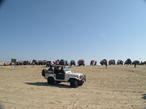 2007 Toyota FJ Cruiser - A group of off-road vehicles gathered on a sandy beach under a clear blue sky.