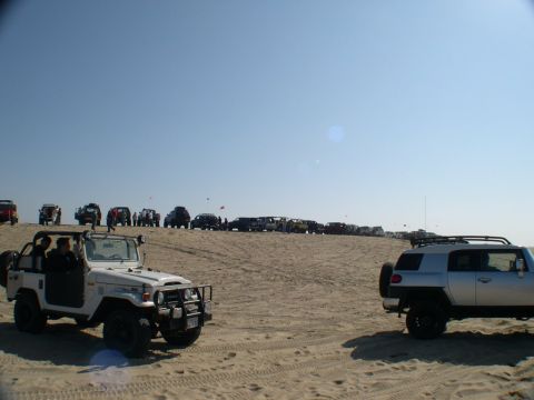 2007 Toyota FJ Cruiser - A group of off-road vehicles are gathered on a sandy terrain under a bright, clear sky.