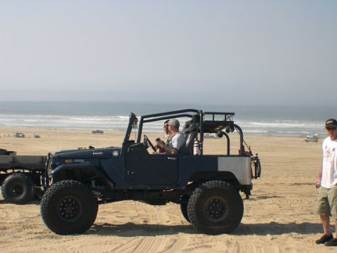 2007 Toyota FJ Cruiser - A modified vintage Toyota Land Cruiser is parked on a beach with the ocean in the distance.