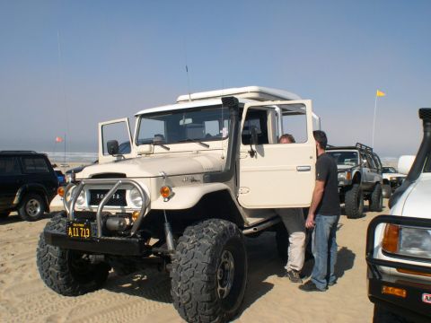2007 Toyota FJ Cruiser - Several off-road vehicles are parked on a sandy beach under a clear sky.