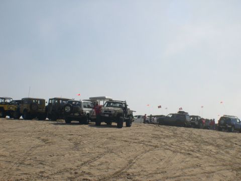 2007 Toyota FJ Cruiser - A convoy of off-road vehicles, including a 2007 Toyota FJ Cruiser, gathered on a sandy beach under a clear sky.