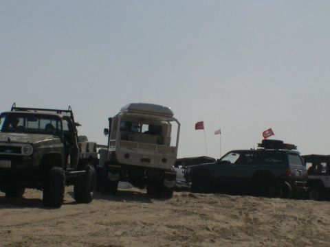 2007 Toyota FJ Cruiser - Multiple off-road vehicles are parked on a sandy beach with flags in the background.