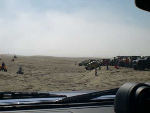 2007 Toyota FJ Cruiser - A group of vehicles and people gathered on sandy terrain under a hazy sky.