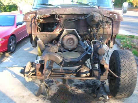 1978 Ford F-250 - Front end of a 1978 Ford F-250 disassembled for work, with a red car parked nearby.