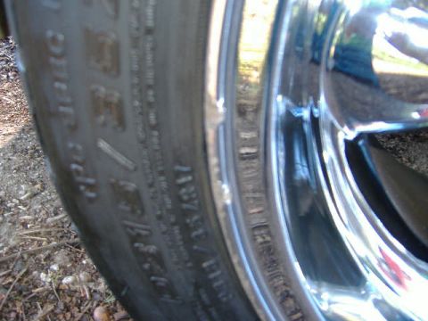 1999 Ford Mustang - A close-up view of a vehicle's tire and chrome wheel, showing details of the tire's tread and sidewall markings.