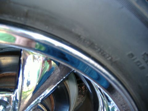 1999 Ford Mustang - A close-up view of a chrome wheel and tire, with some text visible on the tire's sidewall.