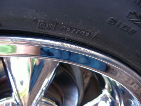 1999 Ford Mustang - A close-up view of a tire and a chrome rim, showing some sidewall markings.