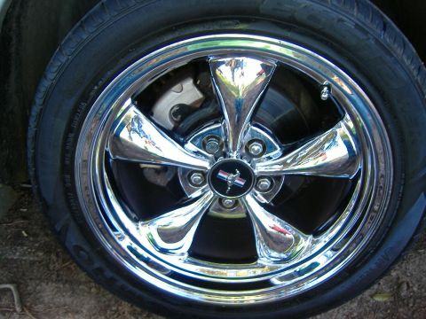 1999 Ford Mustang - Close-up of a chrome wheel the iconic Mustang emblem, with visible tire sidewall details.