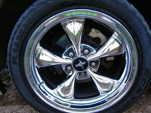 1999 Ford Mustang - Close-up of a chrome wheel with a Mustang emblem, likely from a 1999 Ford Mustang.