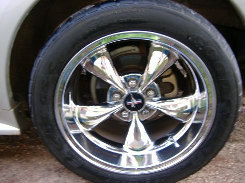 1999 Ford Mustang - Close-up of a chrome five-spoke wheel the iconic Mustang logo, likely from a 1999 model.