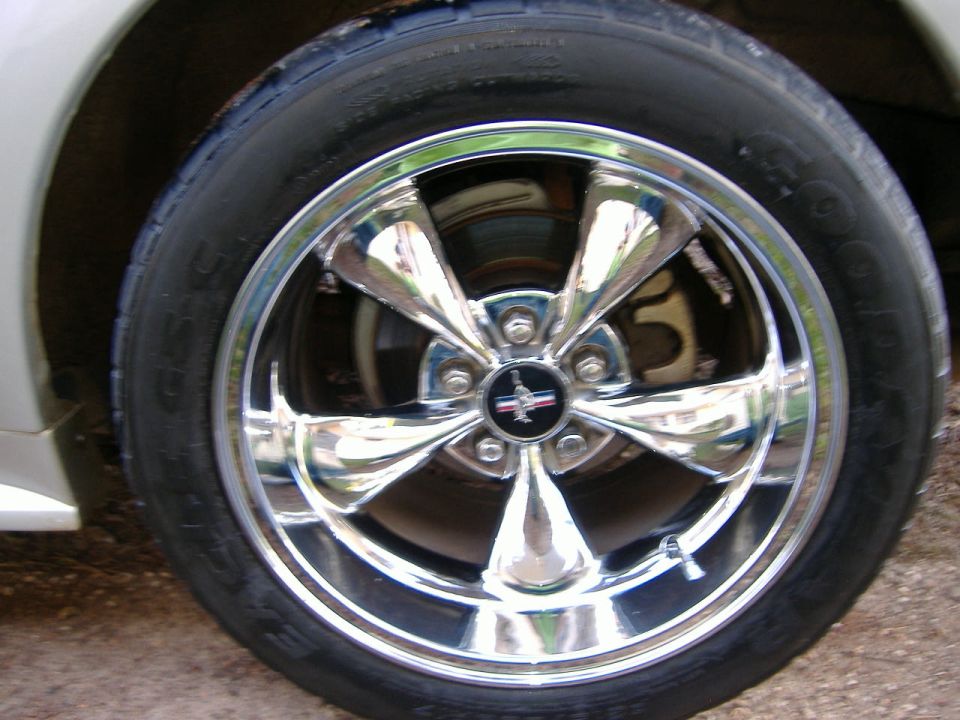 Chrome five-spoke wheel with Mustang logo on 1999 Ford Mustang