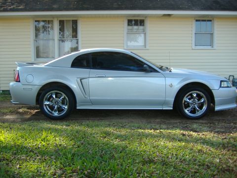 1999 Ford Mustang - Side view of a silver 1999 Ford Mustang coupe with chrome wheels.