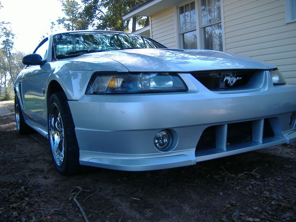 Silver Ford Mustang with chrome wheels, front bumper, and grille with a horse emblem