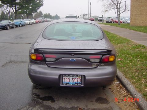1996 Ford Taurus - Rear view of a 1996 Ford Taurus sedan parked on a wet street.