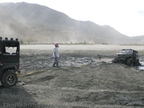 1987 Suzuki Samurai - Two off-road vehicles are stuck in mud, with one partially submerged in a puddle.