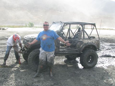1987 Suzuki Samurai - A muddy 1987 Suzuki Samurai is stuck in the mud with two people posing next to it.