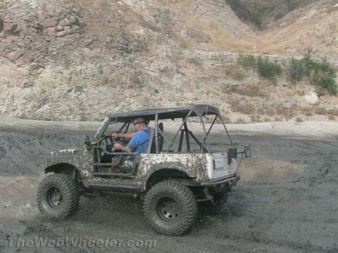 1987 Suzuki Samurai - A 1987 Suzuki Samurai navigates a muddy terrain, kicking up dirt as it goes.