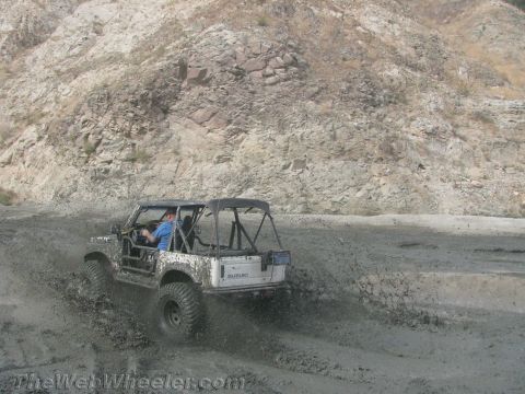 1987 Suzuki Samurai - Suzuki Samurai navigating a muddy terrain with a driver inside.