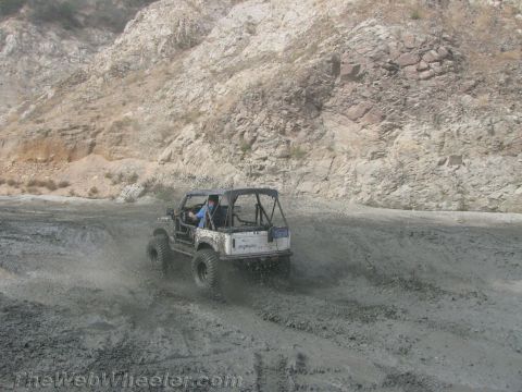 1987 Suzuki Samurai - A Suzuki Samurai navigates a muddy off-road trail, sending dirt flying.