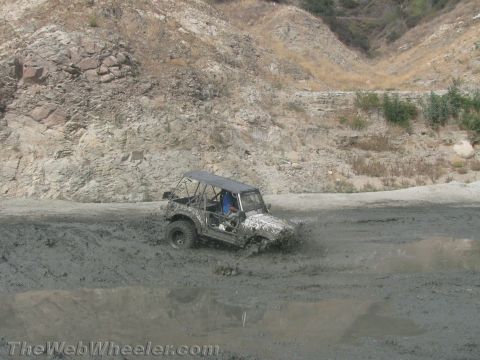 1987 Suzuki Samurai - A 1987 Suzuki Samurai navigates a muddy terrain, kicking up spray.