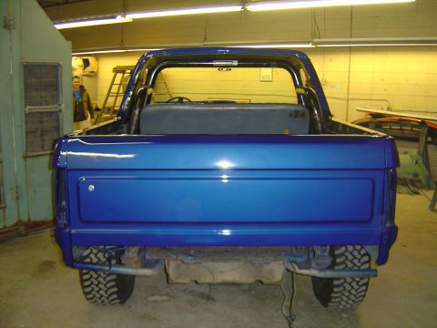 1986 Ford Bronco - Rear view of a blue SUV with a roll bar and off-road tires, possibly from the 1980s.
