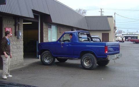 1986 Ford Bronco - A blue 1986 Ford Bronco is seen from the 3/4 front angle, exiting a building.