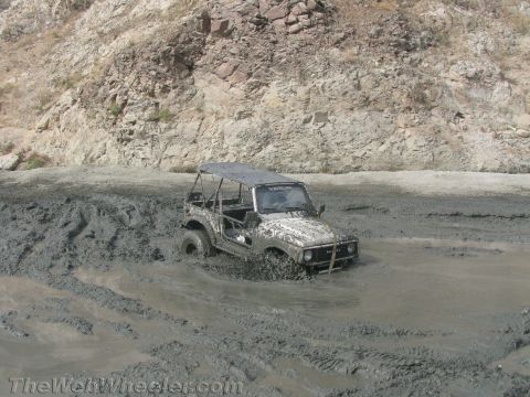 1987 Suzuki Samurai - Suzuki Samurai navigating a muddy terrain, tires deep in the mire.