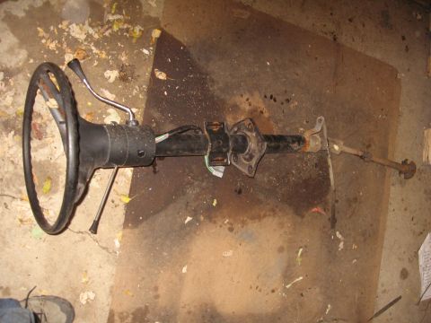 1979 Ford Bronco - A disassembled steering column and wheel lies on a cluttered floor, suggesting a repair or restoration project.