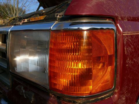 1988 Ford Bronco - Close-up of the front headlight and amber turn signal on a red 1988 Ford Bronco.