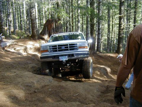 1994 Ford Explorer - A white 1994 Ford Explorer navigates a rocky, wooded trail during an off-road event.