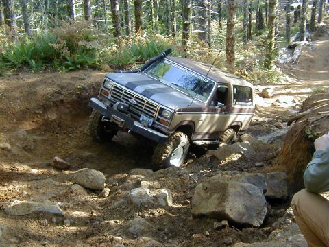 1994 Ford Explorer - This Ford Bronco is tackling a challenging off-road course in a wooded area.