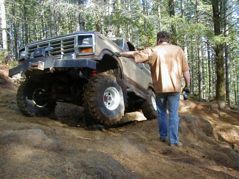 1994 Ford Explorer - A modified off-road vehicle navigates a challenging terrain in a forest setting.