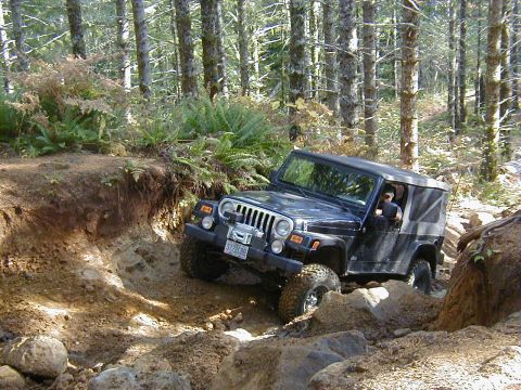 1994 Ford Explorer - A black Jeep Wrangler TJ tackles a challenging off-road trail with steep inclines and large rocks.