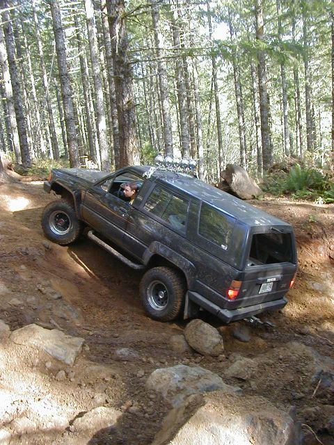 1994 Ford Explorer - Modified SUV navigates a challenging off-road trail through a forest.