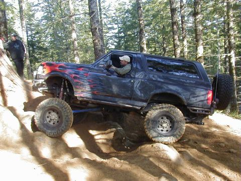 1994 Ford Explorer - Modified 1994 Ford Bronco tackling an off-road trail with a person watching on the side.