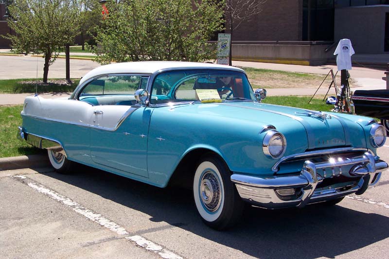 Two-tone turquoise and white 1955 Pontiac hardtop at a car show, whitewall tires