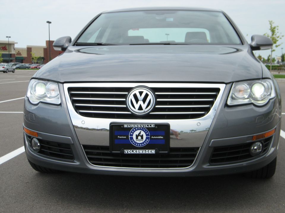 Front view of a gray Volkswagen Passat sedan with Burnsville Volkswagen dealer plate in a parking lot