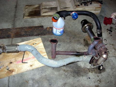 1994 Ford Probe - A disassembled exhaust system component, possibly from a car, is laid out on a concrete floor.